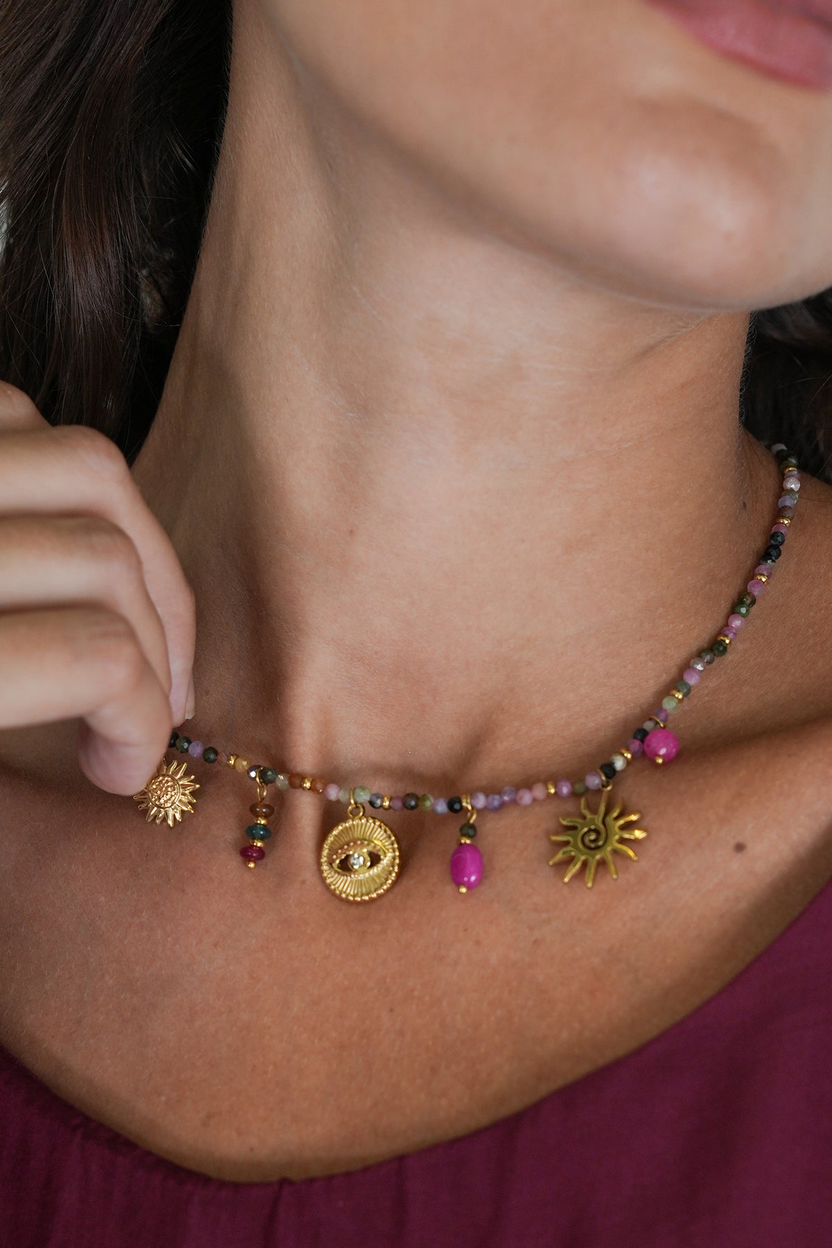 Close-up of a woman wearing a colorful beaded necklace with sun-shaped charms.