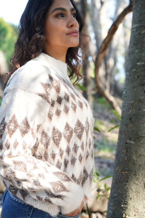 Woman wearing a patterned shawl outdoors near trees